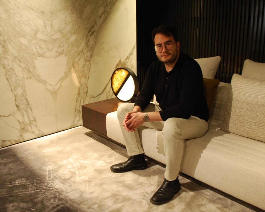 James Apichart Jarvis lounges on a Minotti sofa in a marble room, beside a Brokis Geometric Table lamp.