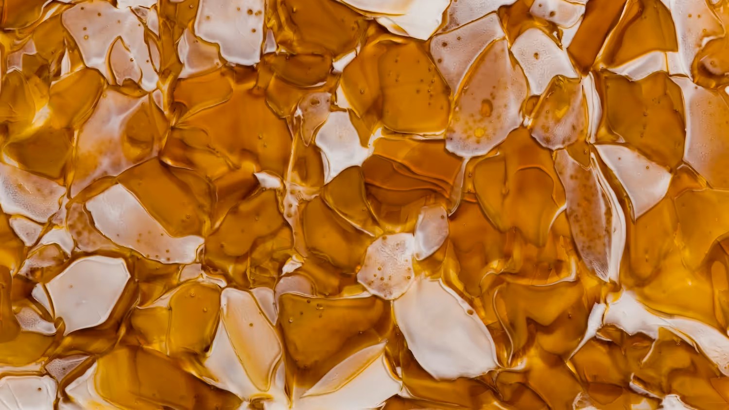 Close-up of amber BROKISGLASS with a luxe, abstract texture, evoking caramelised glass artistry.