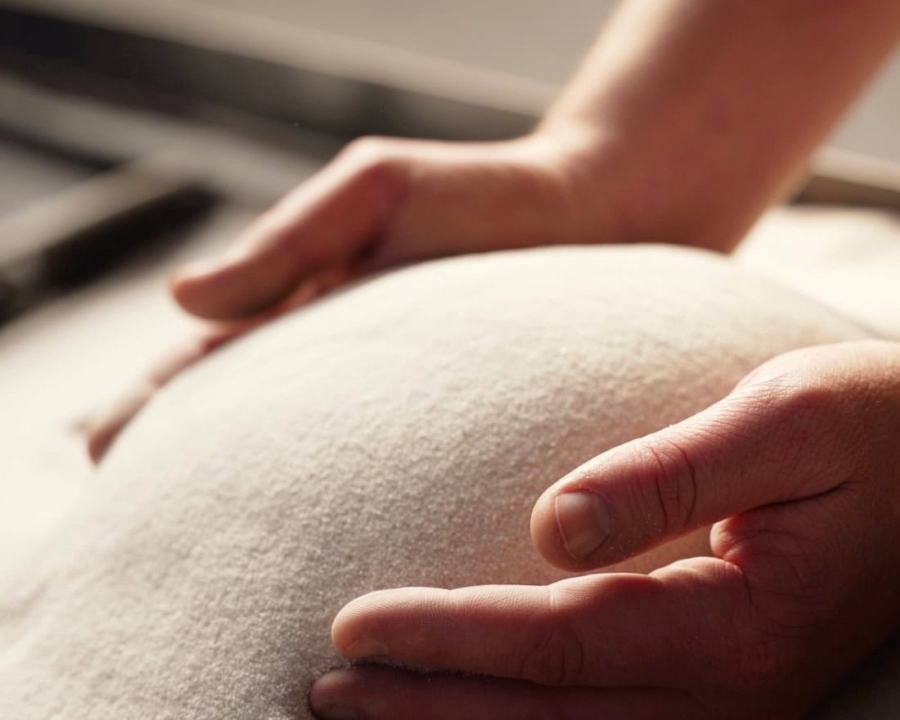 Close-up of hands expertly shaping a sand ball, soft light accentuating its texture and the artisan's meticulous motions.