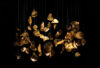 A sculptural cluster of handblown, golden BROKISGLASS leaves floats on fine wires, radiating soft luxury against black.