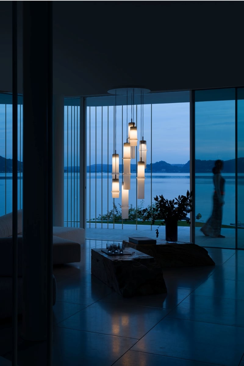 Brokis Bamboo Forest pendants in a modern living room at dusk and serene views of sea and hills.