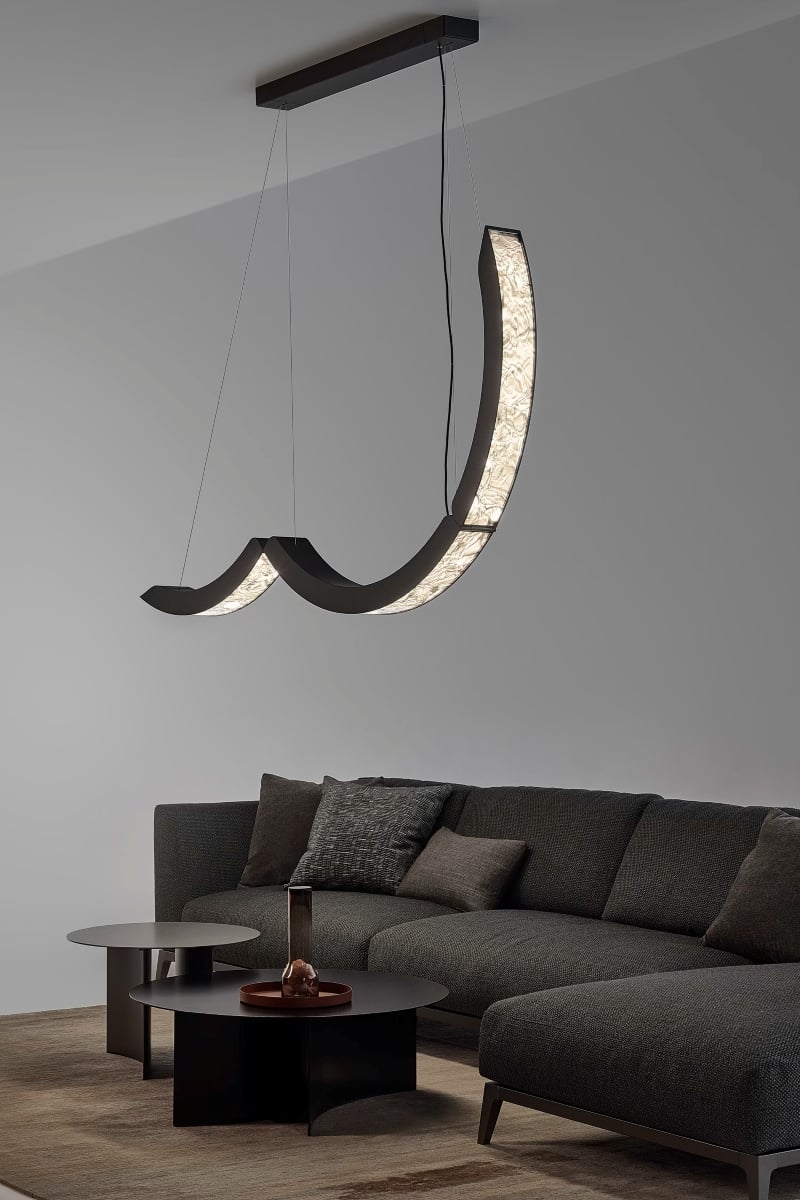 Modern living room with a dark grey sectional, neutral cushions, twin black coffee tables, and a Brokis Elo Chandelier.