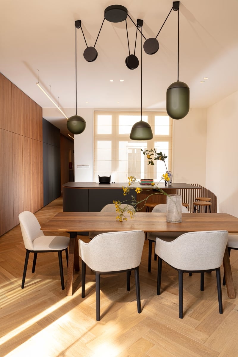 Brokis Planets 3 Set in an elegant dining room with a wood table, six beige chairs, and floor-to-ceiling window.