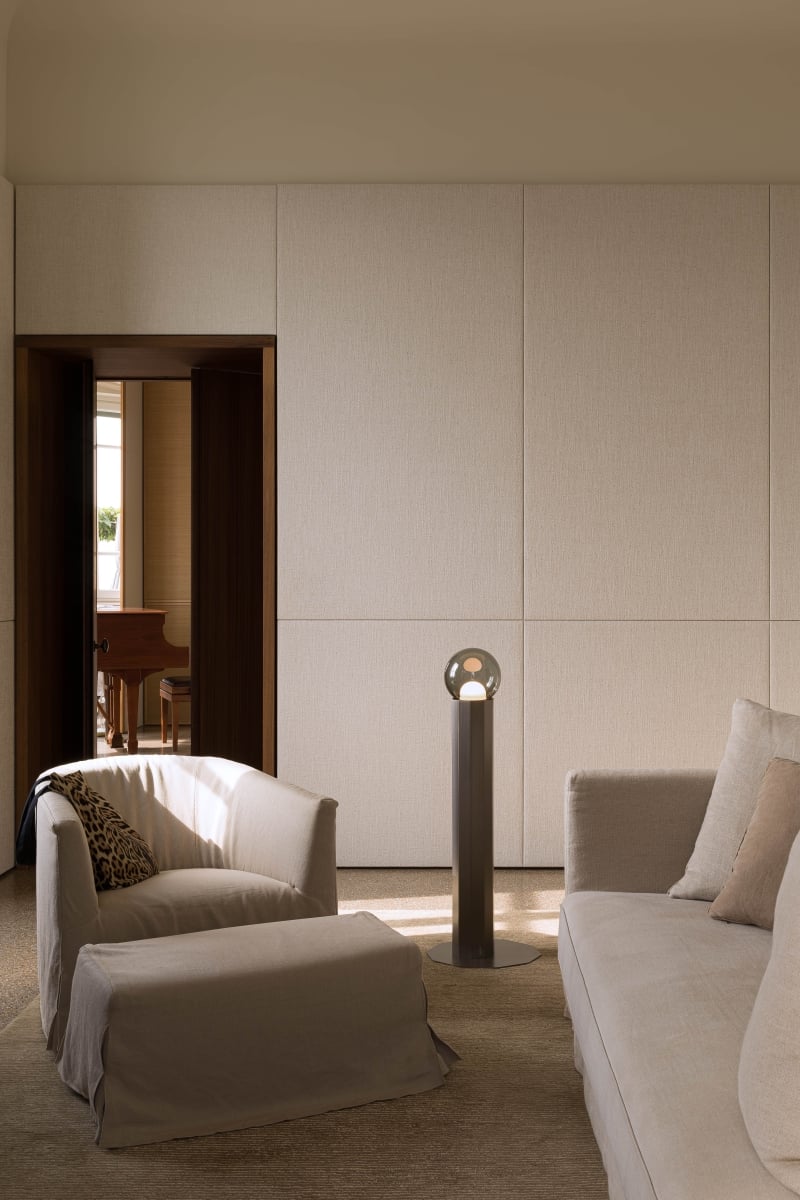 Brokis Prisma Floor Small 600 in a minimalist living room with beige tones, and sunlight illuminating a grand piano beyond.