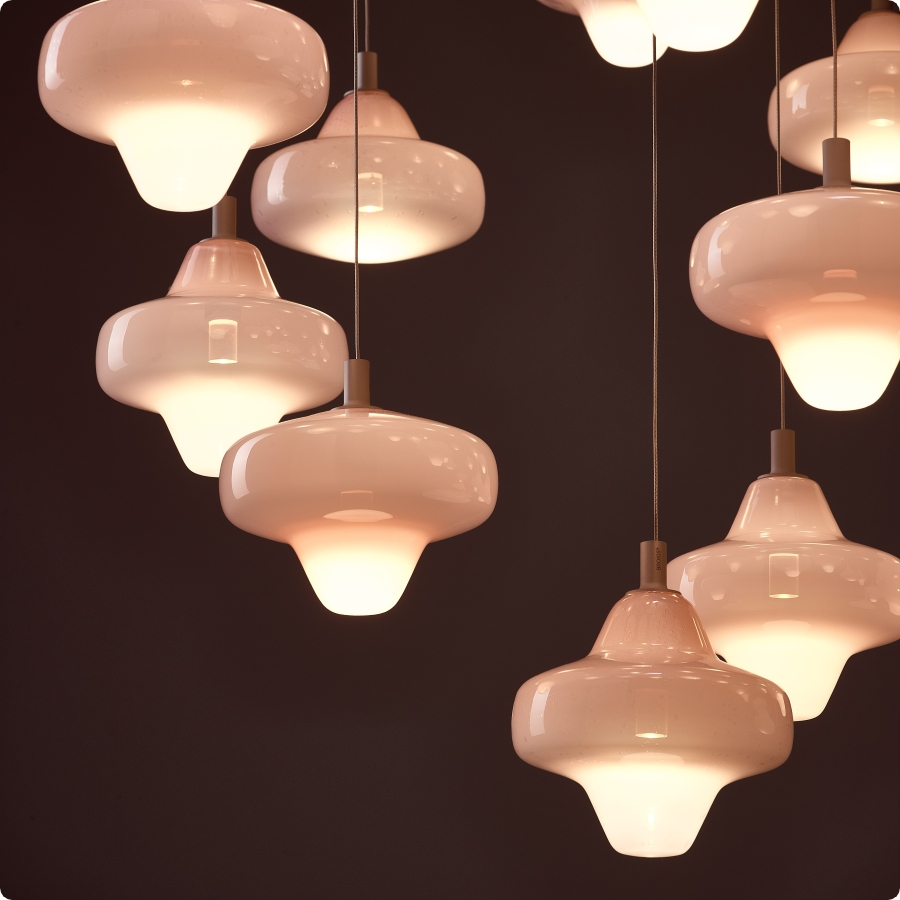 Brokis Starcloud pendants float at varied heights, casting a luminous, luxurious glow against a dark backdrop.