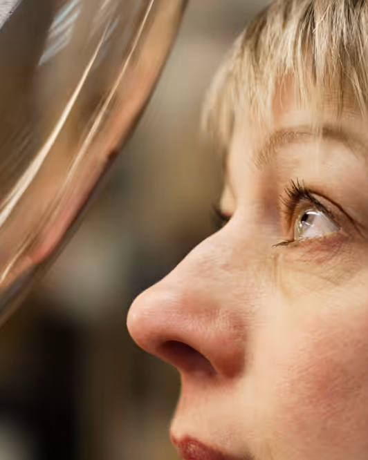 A side profile of a woman with short, fair hair gazing at a Brokis glass shade for quality control.