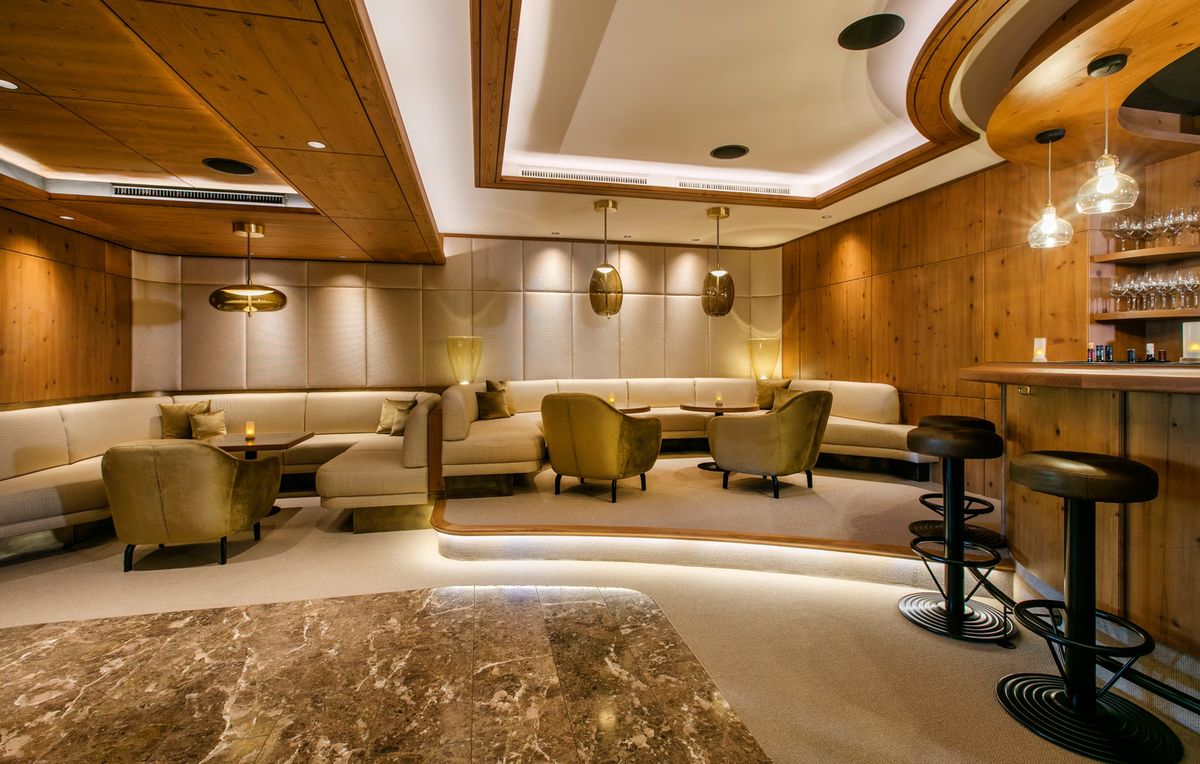 A chic lounge with beige curved sofas, circular tables, and  Brokis Knot pendants glowing with warm ambience.