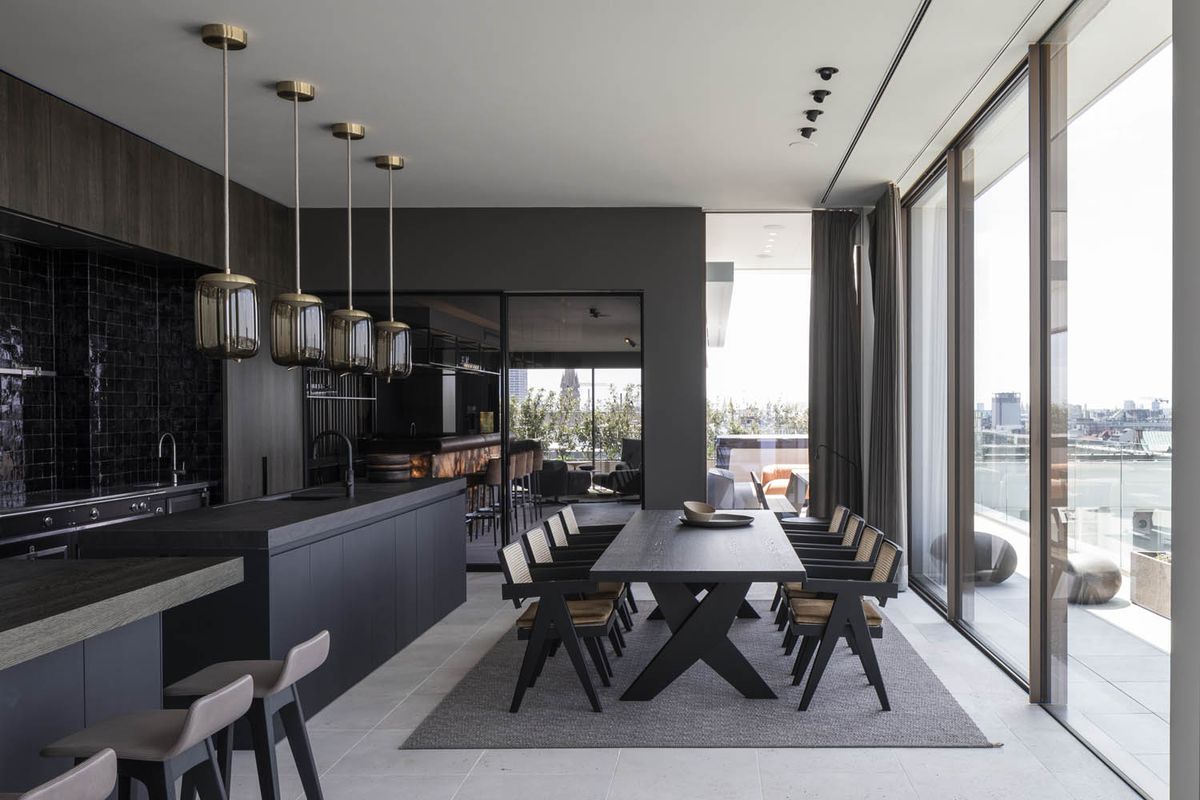 Sophisticated kitchen and dining area with Brokis Knot Cilindro Pendants, city views, and luxe black finishes.