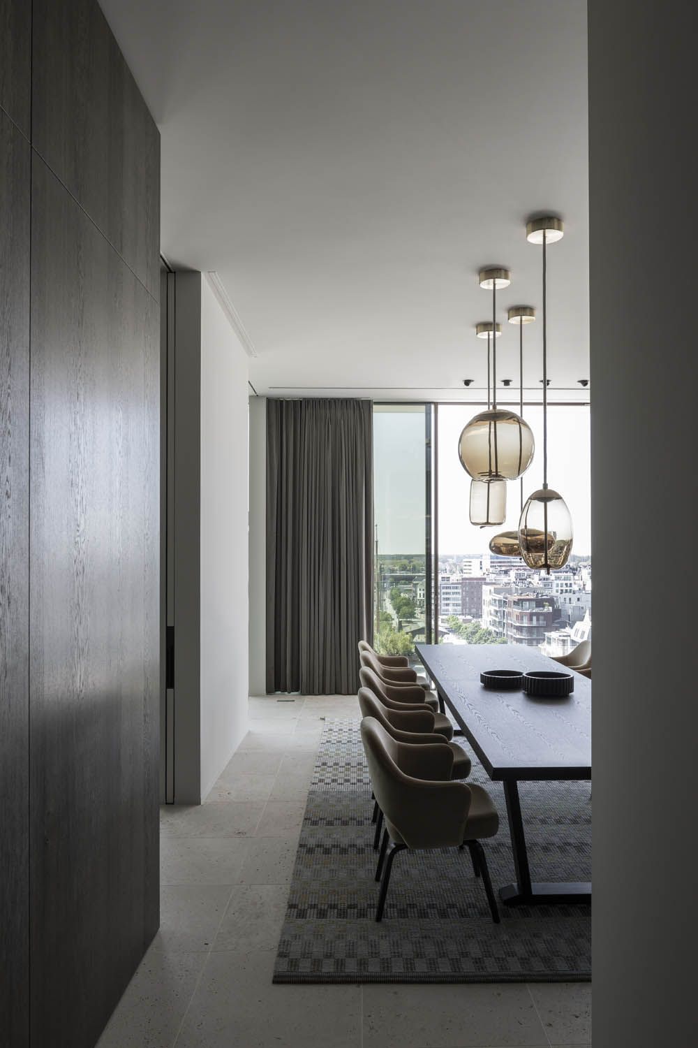 Sleek dining room with a long dark table, eight cushioned chairs, and Brokis Knot pendants.