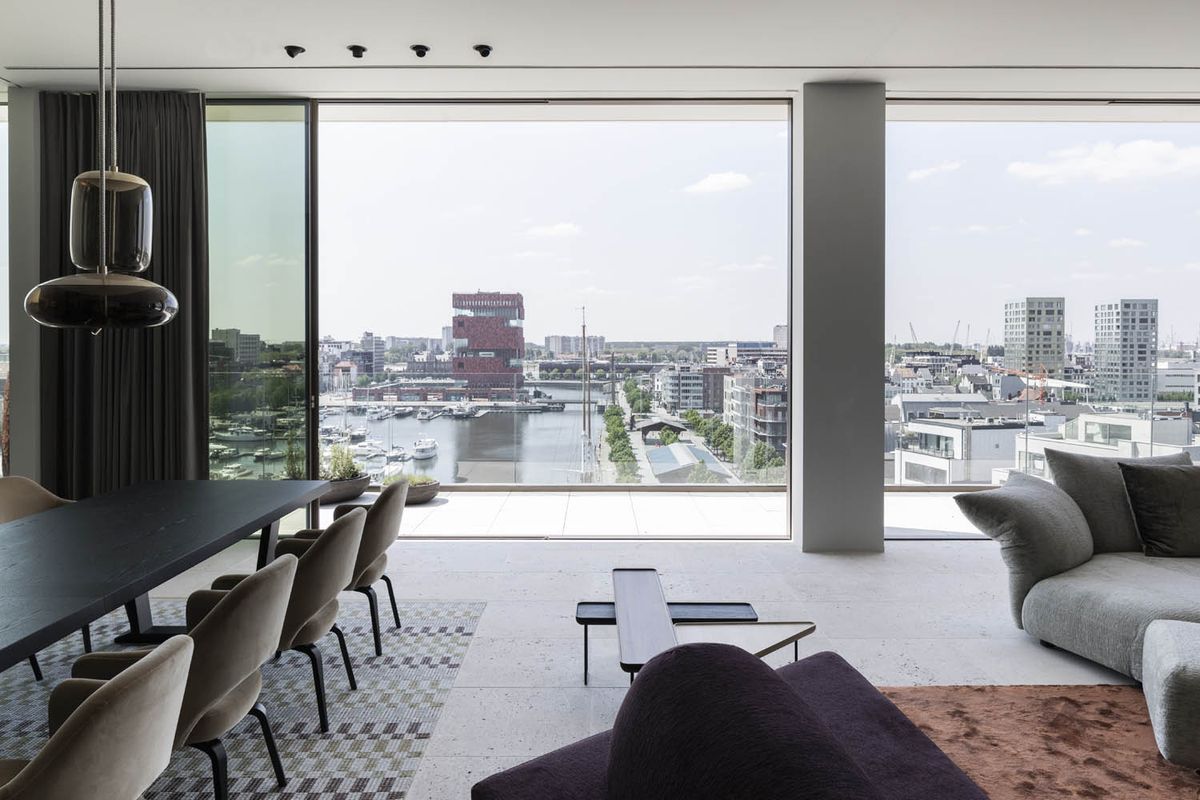 An open-plan living and dining area with floor-to-ceiling windows and Brokis Knot pendants; sweeping harbour skyline views.