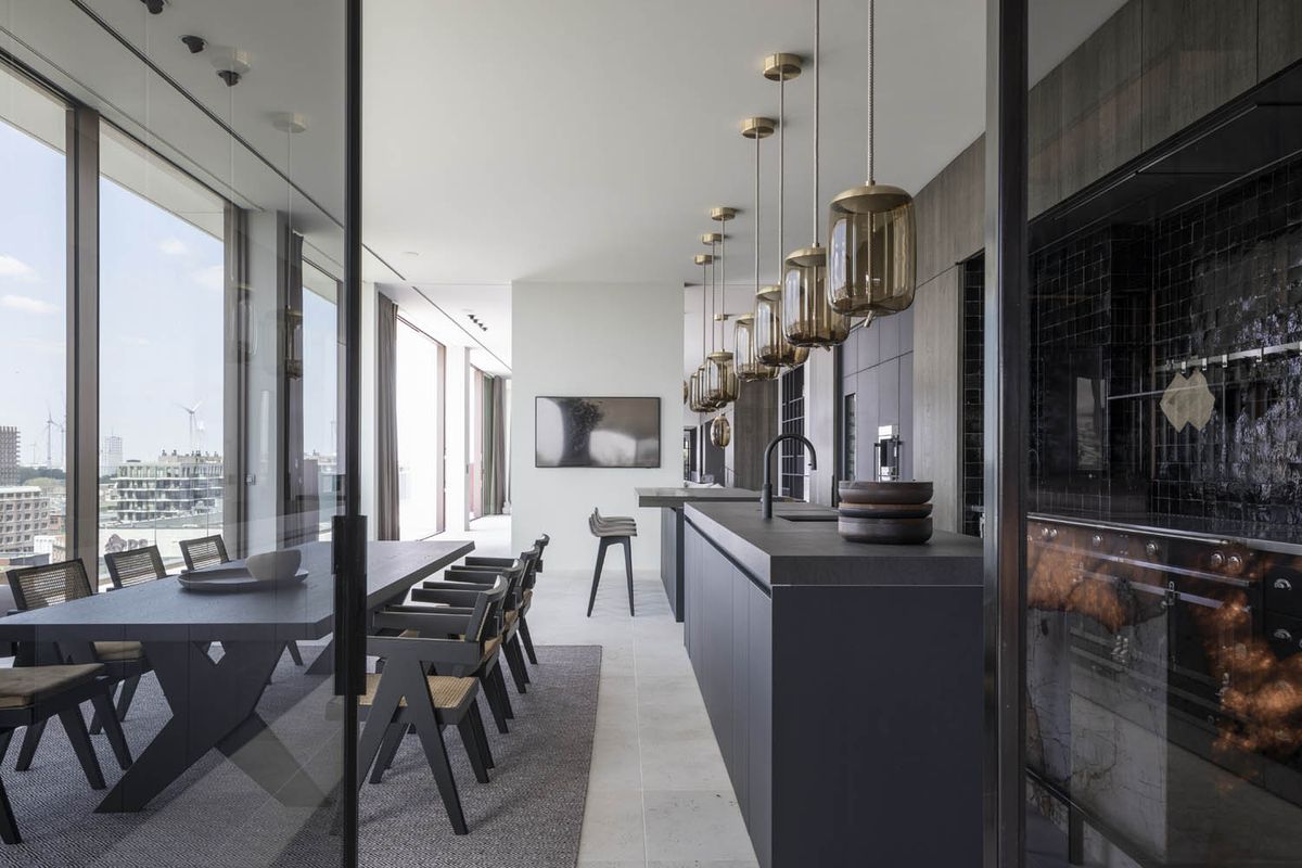 Luxurious kitchen and dining area with Brokis Knot Cilindro pendants, city views, and sleek contemporary finishes.