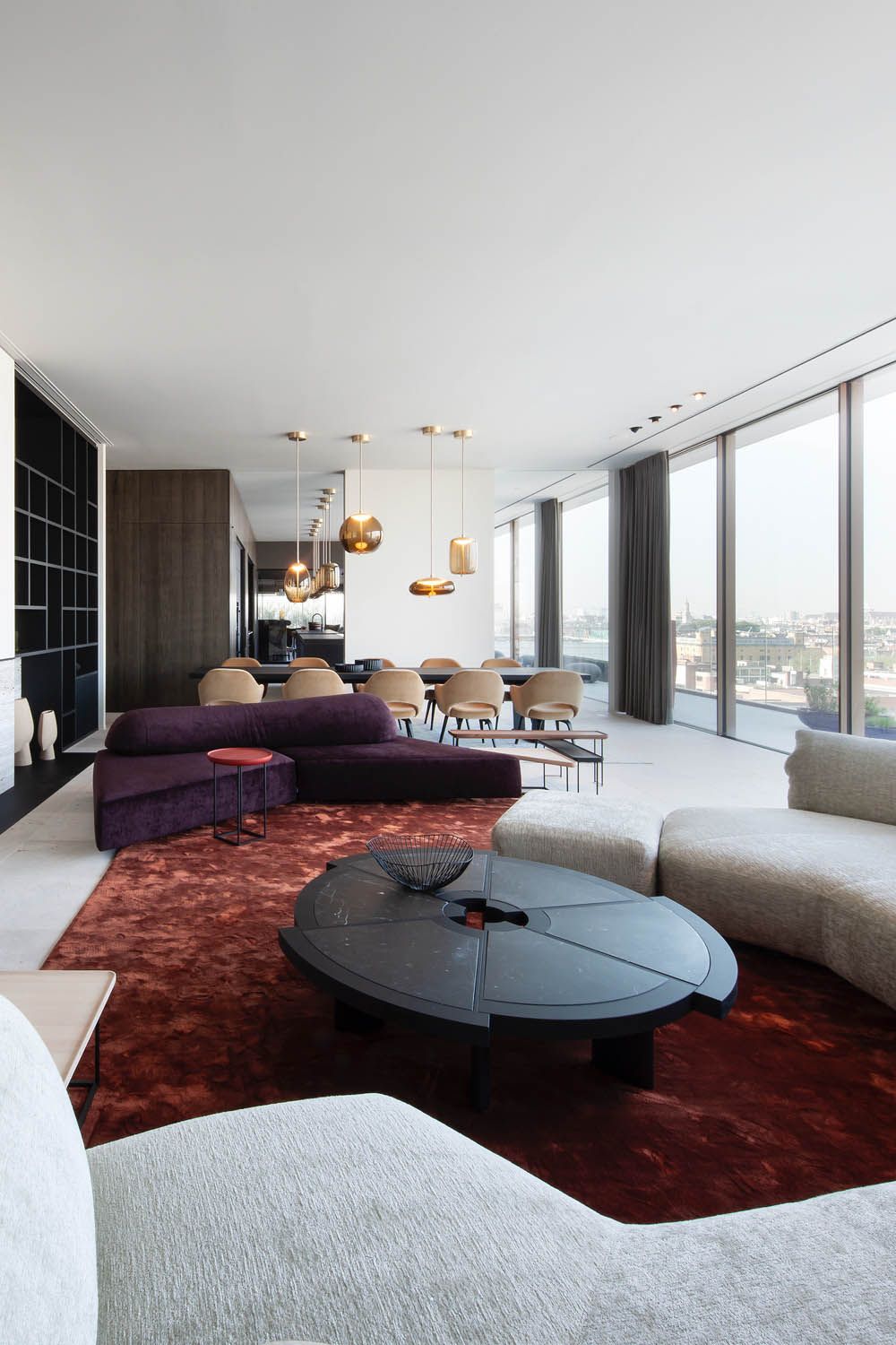 Modern living room with floor-to-ceiling windows, Brokis Knot  pendants, designer sofas, and city views.