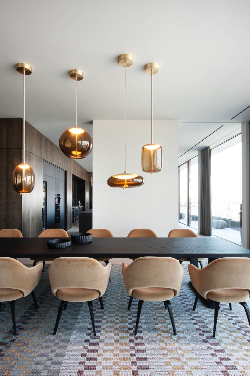 Elegant dining room with long black table, beige chairs, and Brokis Knot pendants. Sheer-lit ambience.