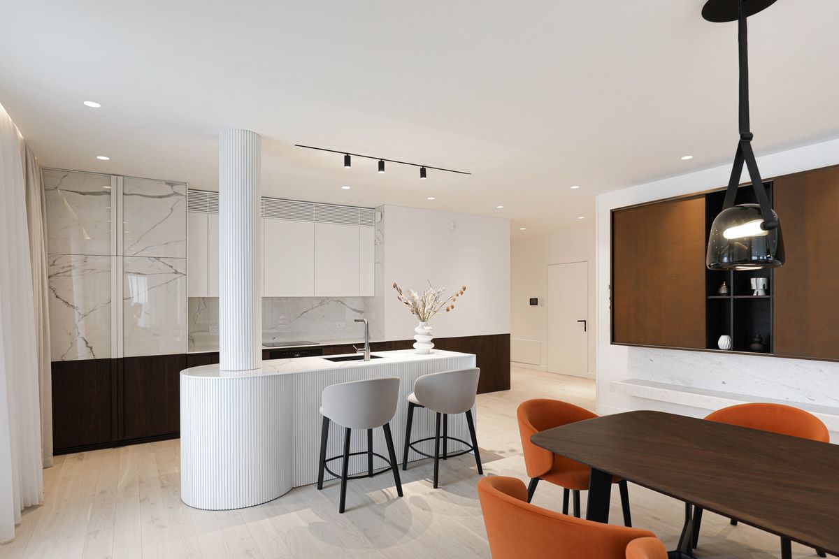 Open-plan kitchen with an island, marble splashback, dark wood accents, dining chairs, and Brokis Mona Medium Pendants.
