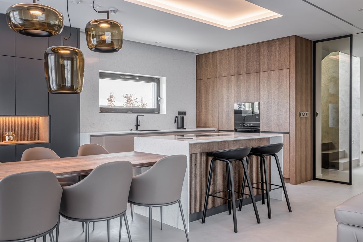 Elegant kitchen with wood and grey tones, Brokis Double pendants, sleek island, and designer dining ensemble.