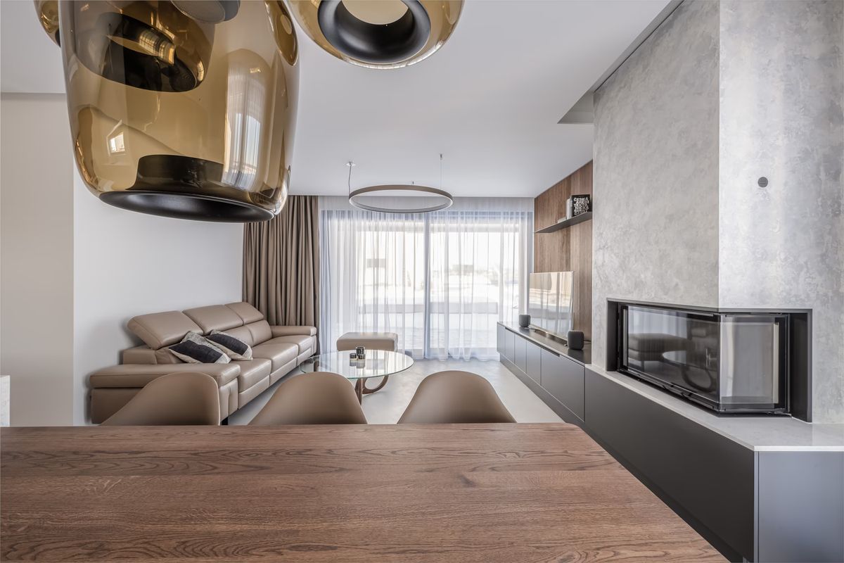 Sophisticated living-dining space with neutral tones, brown leather sofa, sleek TV cabinet, and Brokis Double pendants.