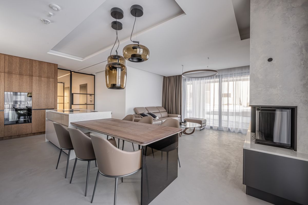 Sleek open-plan space with a wooden dining table, Brokis Double pendants, and luxurious minimalist furnishings throughout.