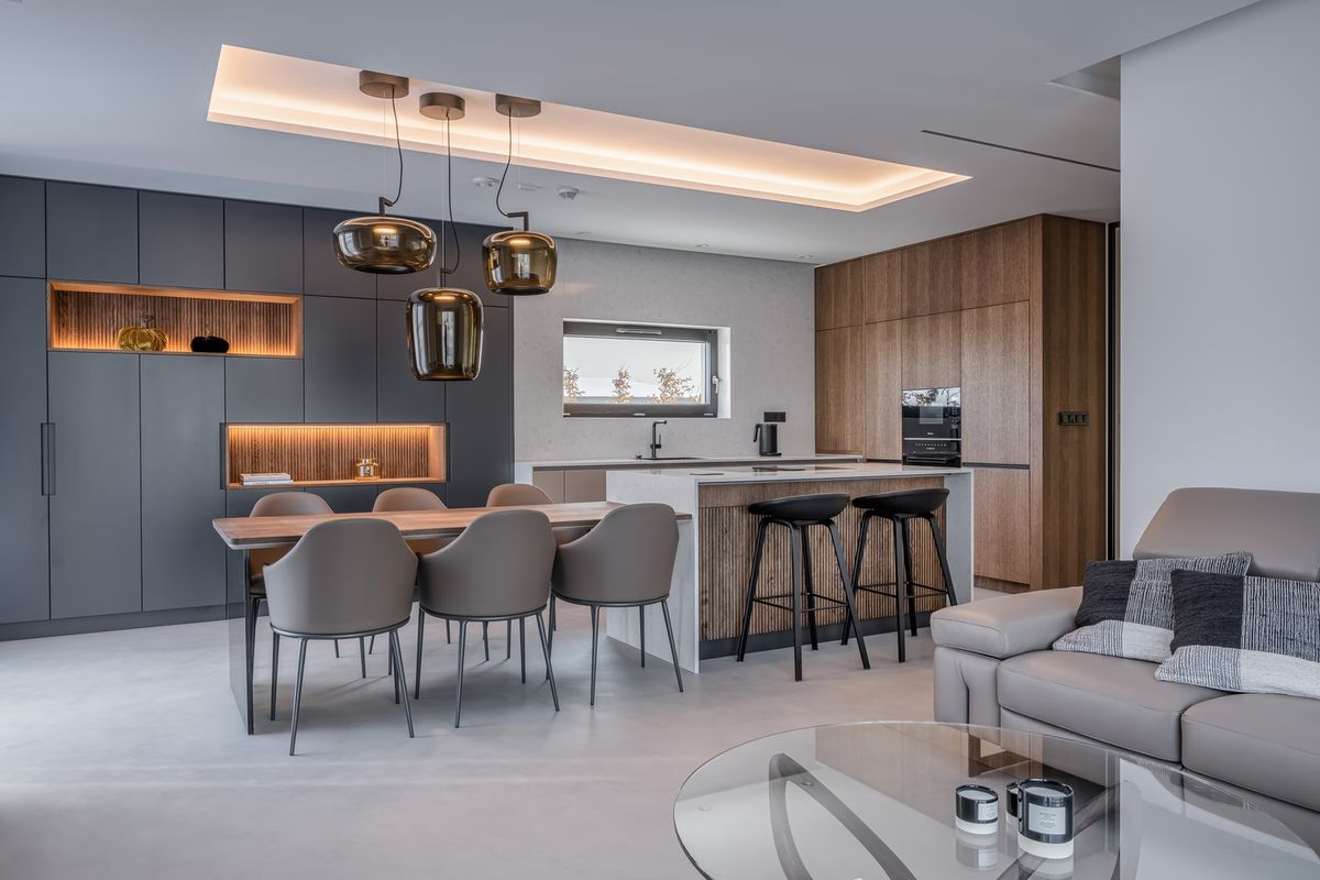 Modern open-plan kitchen with grey cabinetry, wood accents, minimalist decor, and Brokis Double pendants above dining table.