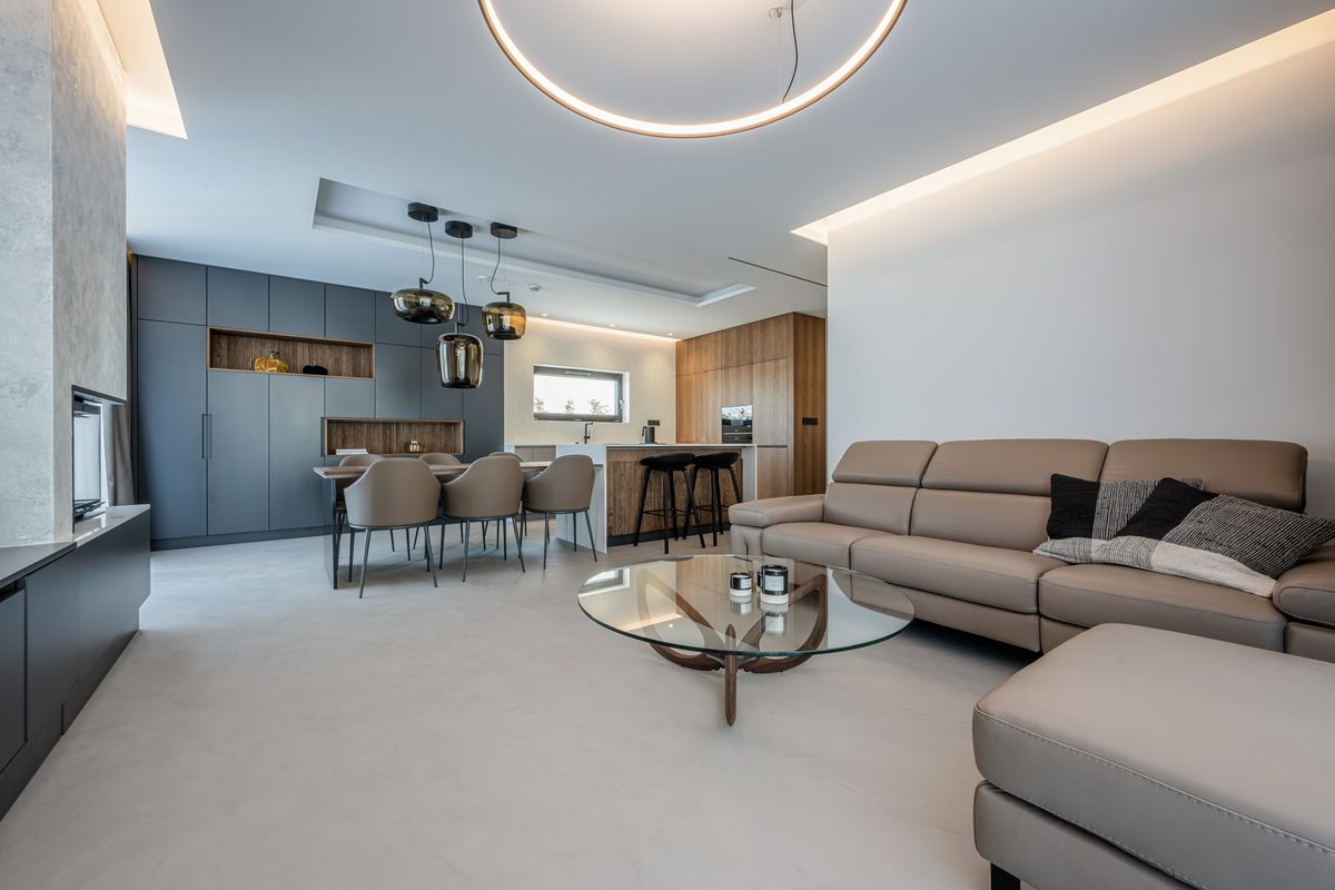 A luxurious open-plan living-dining space with beige leather sofas, glass coffee table, and Brokis Double pendants.