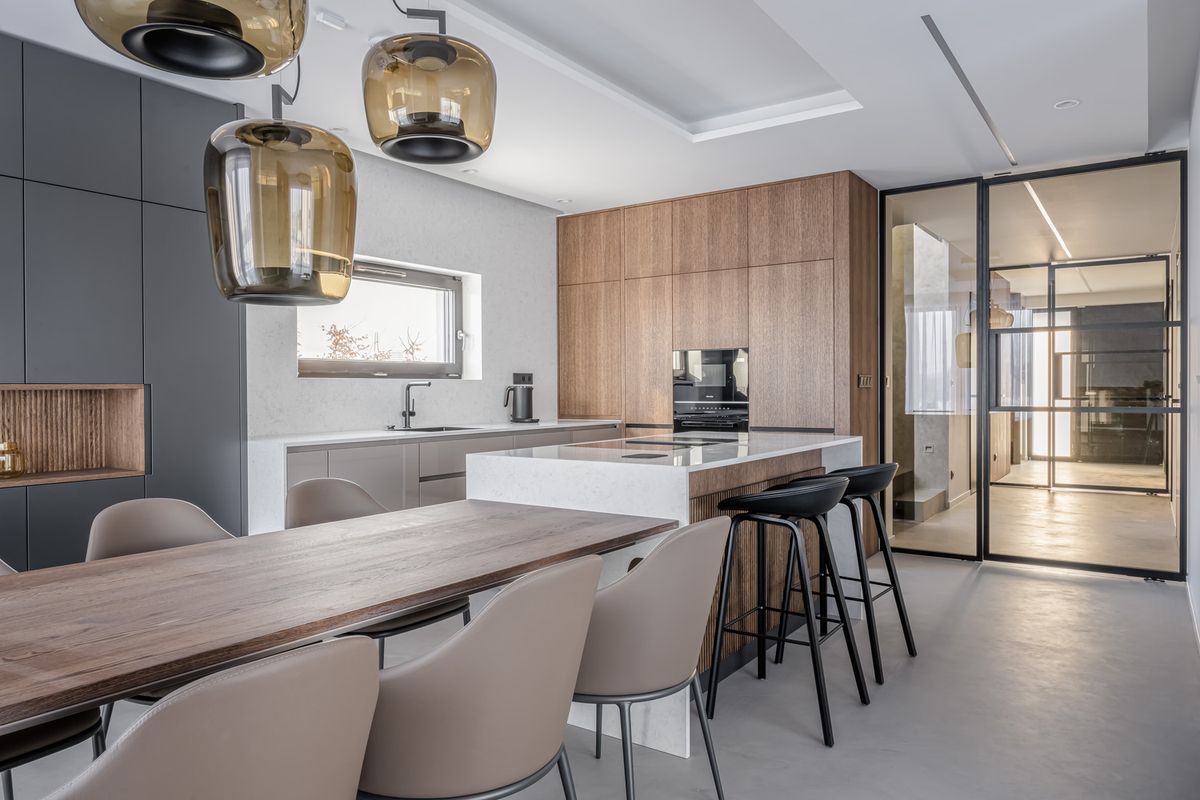 Luxurious kitchen and dining area with brown Brokis Double pendants, island, wooden table, and elegant seating.