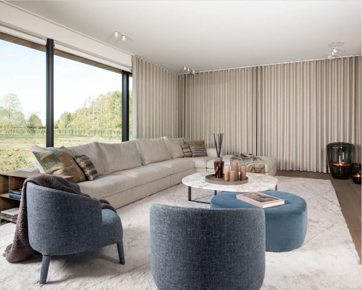 Sophisticated living room with floor-to-ceiling windows, corner sofa, armchairs, marble tables, white rug, Brokis Balloons.