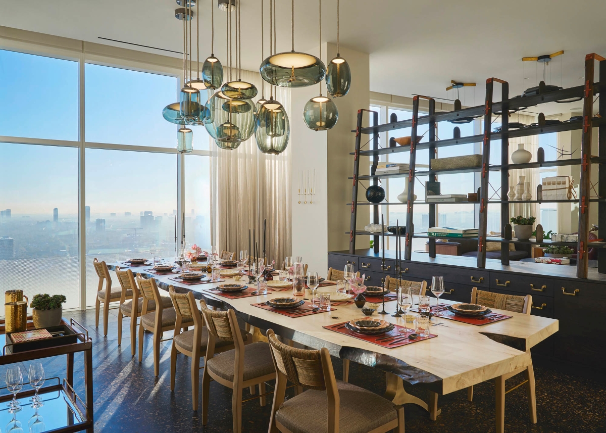 Elegant dining room with a long table set for twelve, decorative plates and flowers, Brokis Knot pendants above.