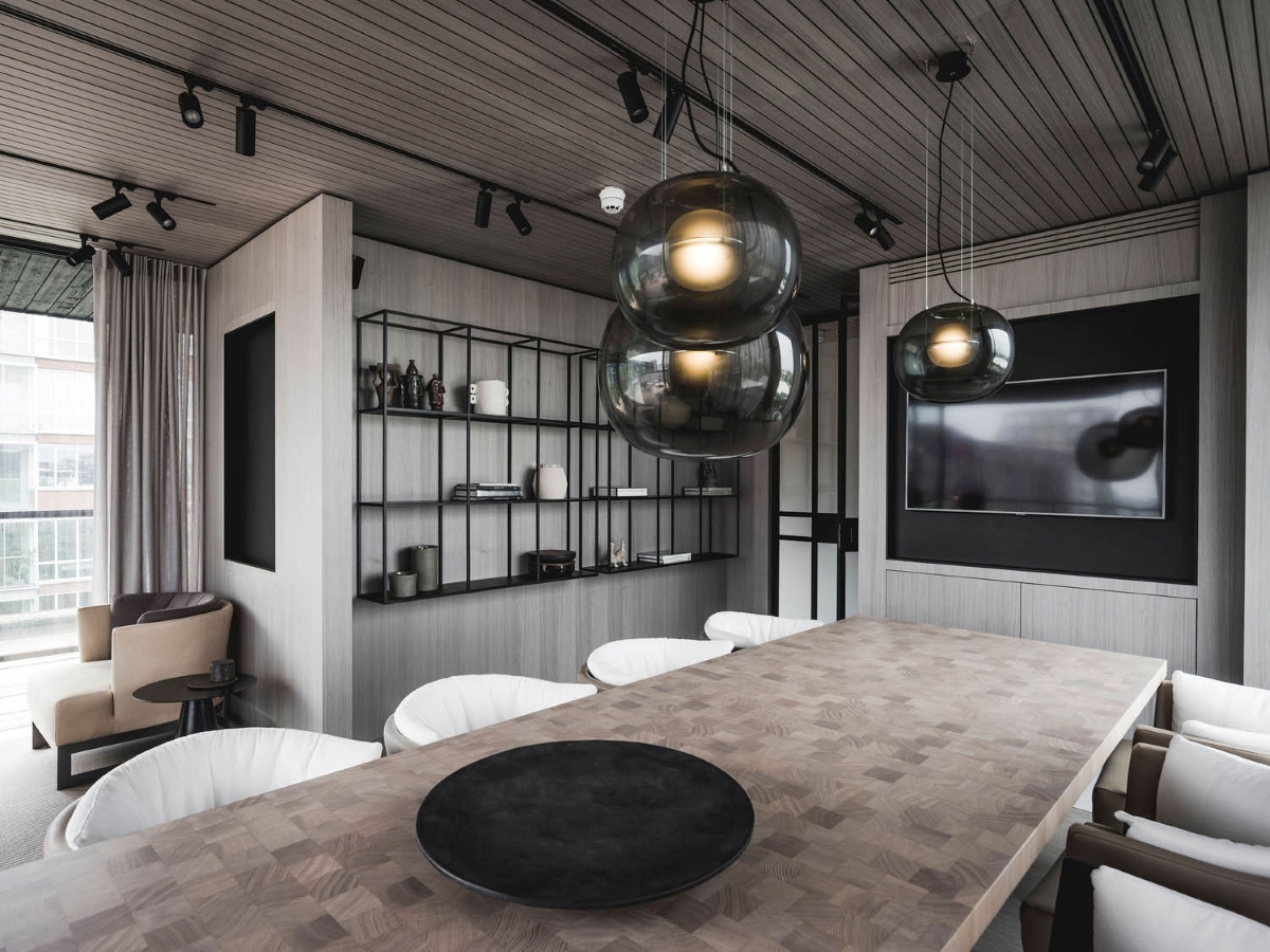 Sleek meeting space with a wooden table, white chairs, sculptural Big One pendants, and luxurious accents.