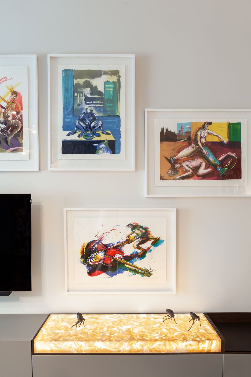 Four vibrant abstract paintings hang above a BROKISGLASS backlit console table with amber triplex opal.