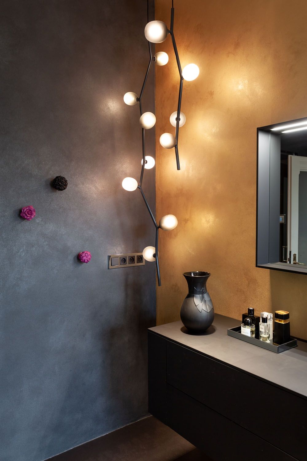 Luxurious bathroom with matt black and gold walls, Brokis Ivy Vertical pendants, and elegant floral accents.