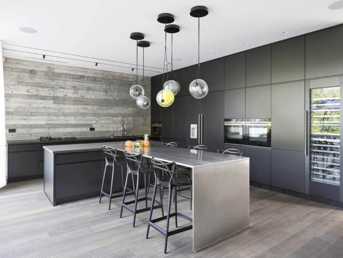Sleek kitchen with matt black cupboards, stainless island, Brokis Capsula Single Pendants, and luxurious wine fridge wall.