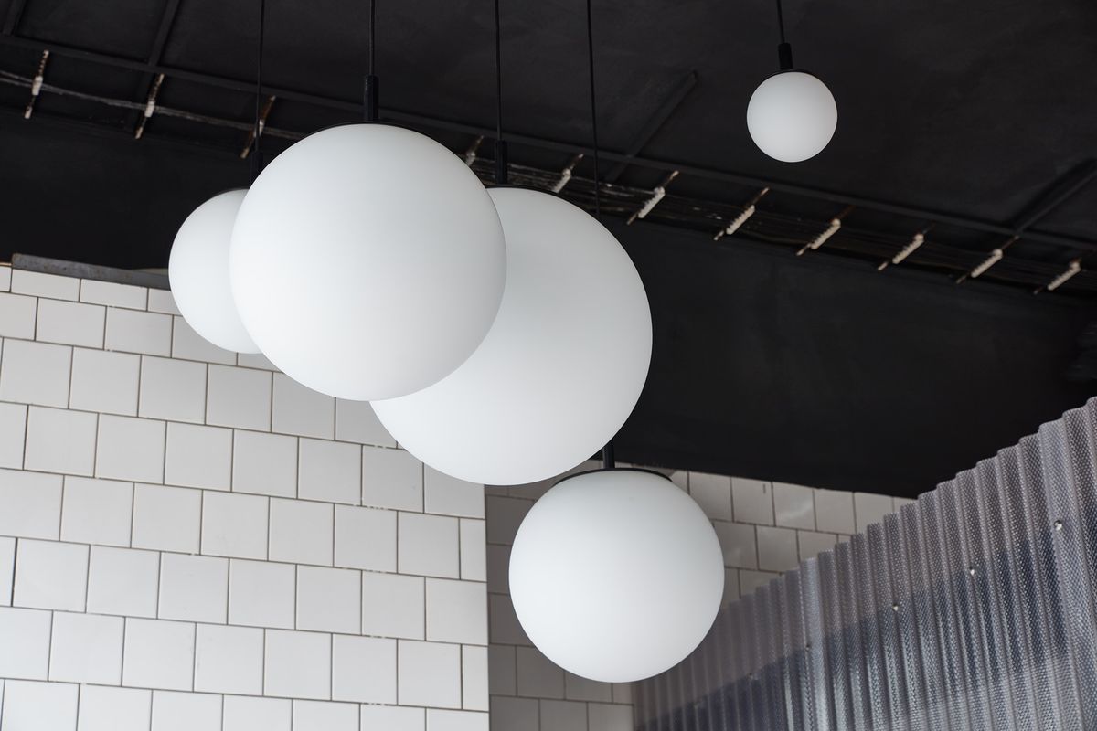 Brokis Sfera pendant cluster from a black ceiling above white tiled walls, exuding modern luxury.