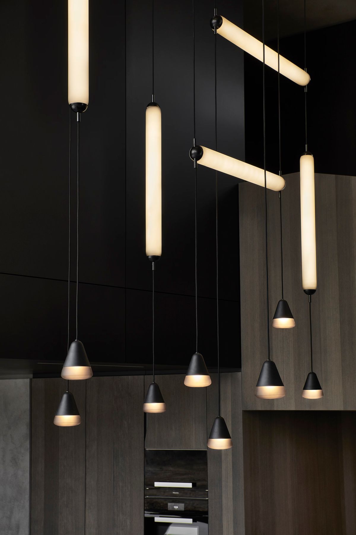 Sleek interior with  Brokis Puro pendants casting warm glow above wood panelling and matt cabinetry.