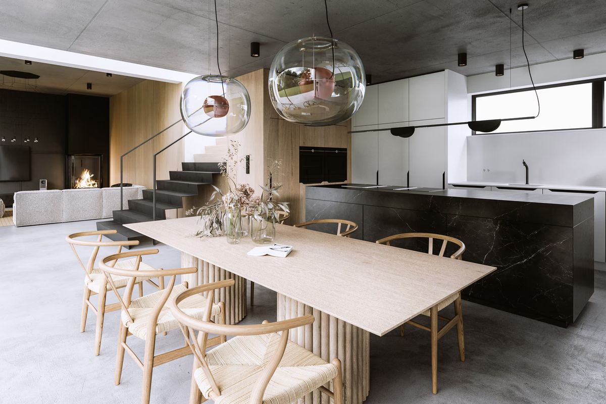 Sleek open-plan kitchen and dining area with black marble island, Brokis Big One Large pendants, and refined neutral décor.