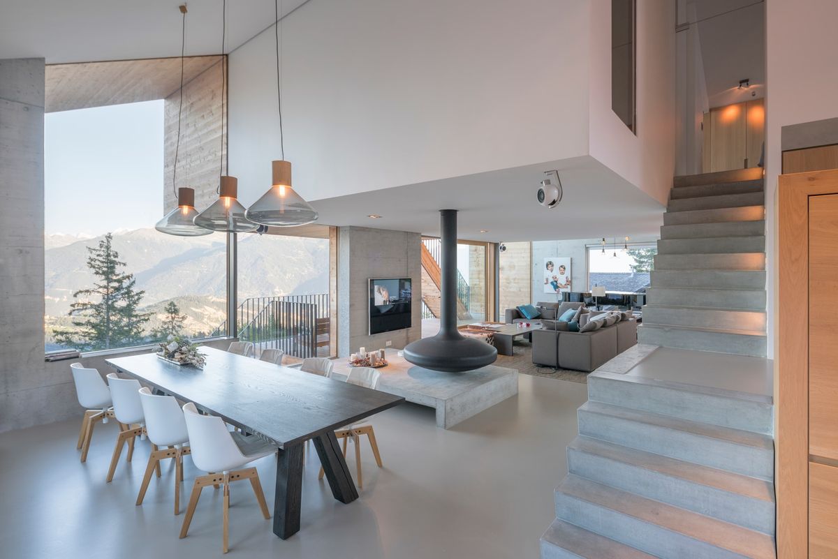 Airy open-plan interior with panoramic mountain views, a long dining table beneath Brokis Muffins Wood 03 Pendants.