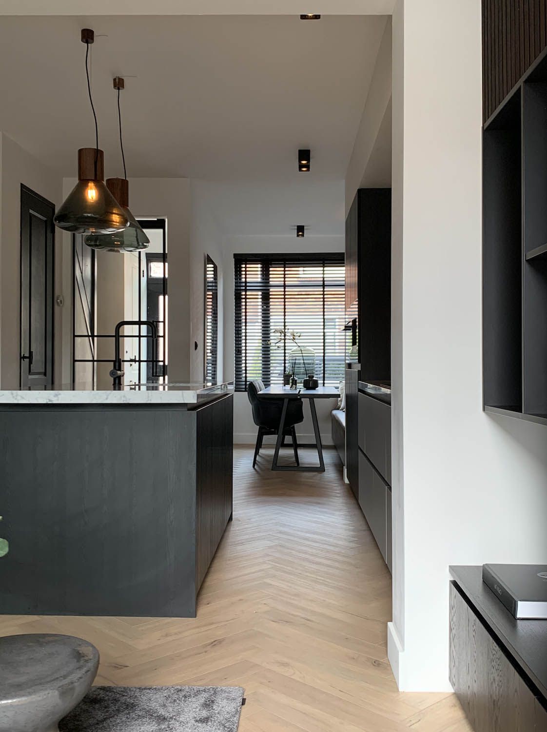 Kitchen with cupboards, marble worktops, Brokis Muffins Wood 03B pendants, herringbone floors, and sunlit dining area.