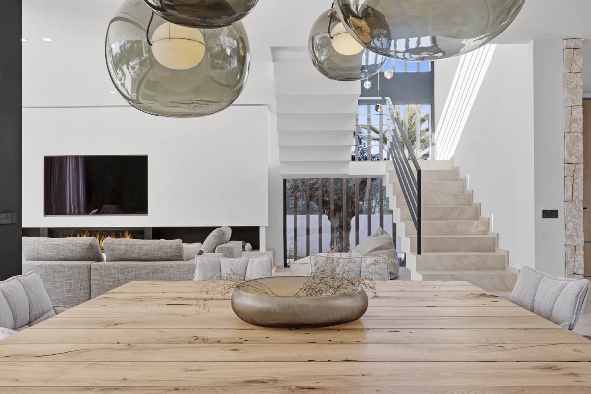 A luxurious minimalist space with a light wood dining table, neutral chairs, and Brokis Big One Pendants above.