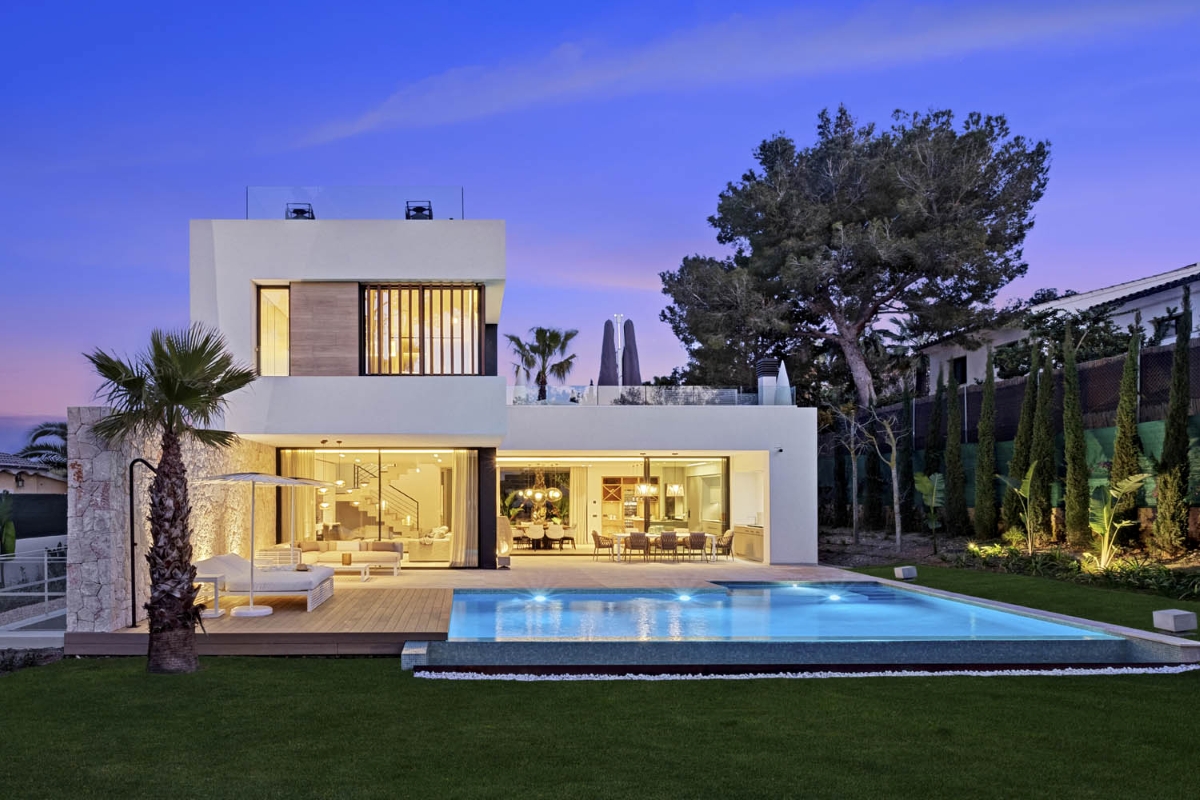 A luxurious house with a pool and mature trees, softly illuminated to create a serene, resort-like atmosphere.