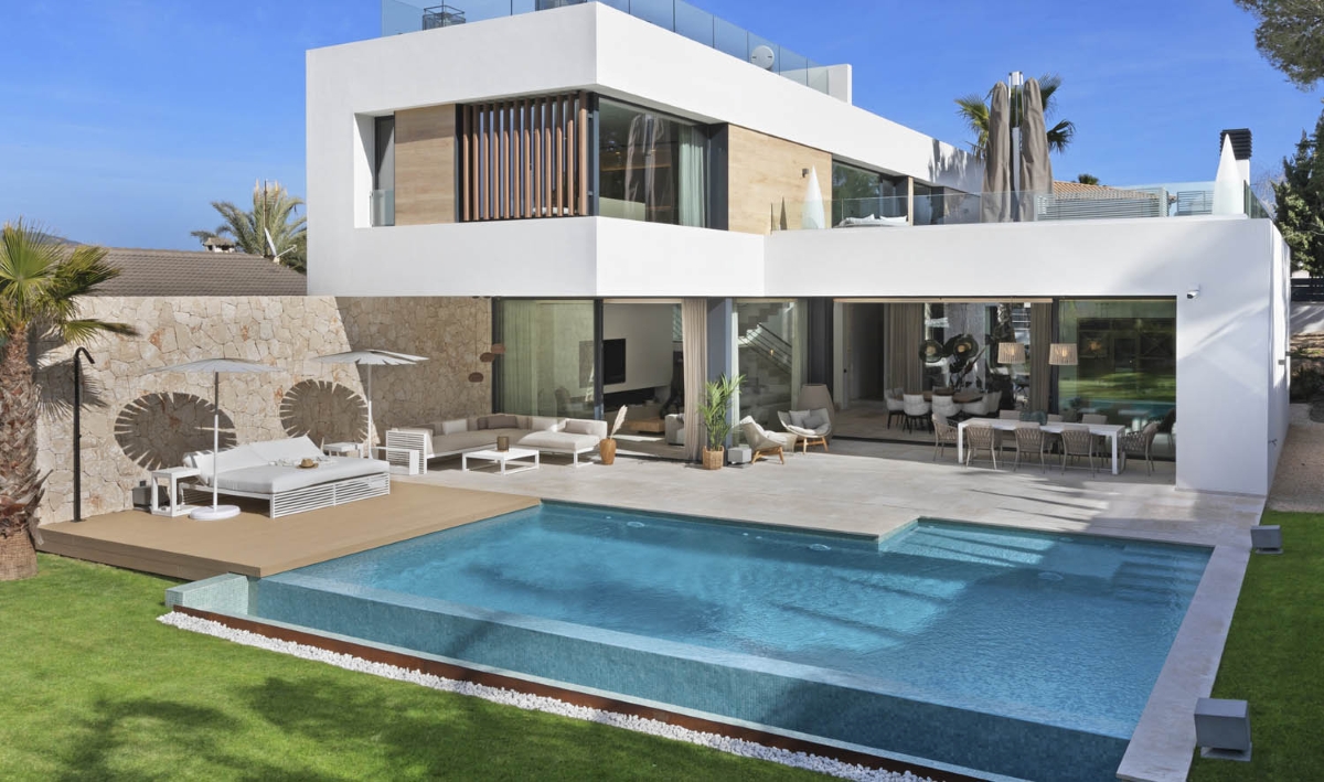 Sleek two-storey white home with vast glass windows, wood accents, chic Brokis lighting, pool, palms, and manicured lawn.